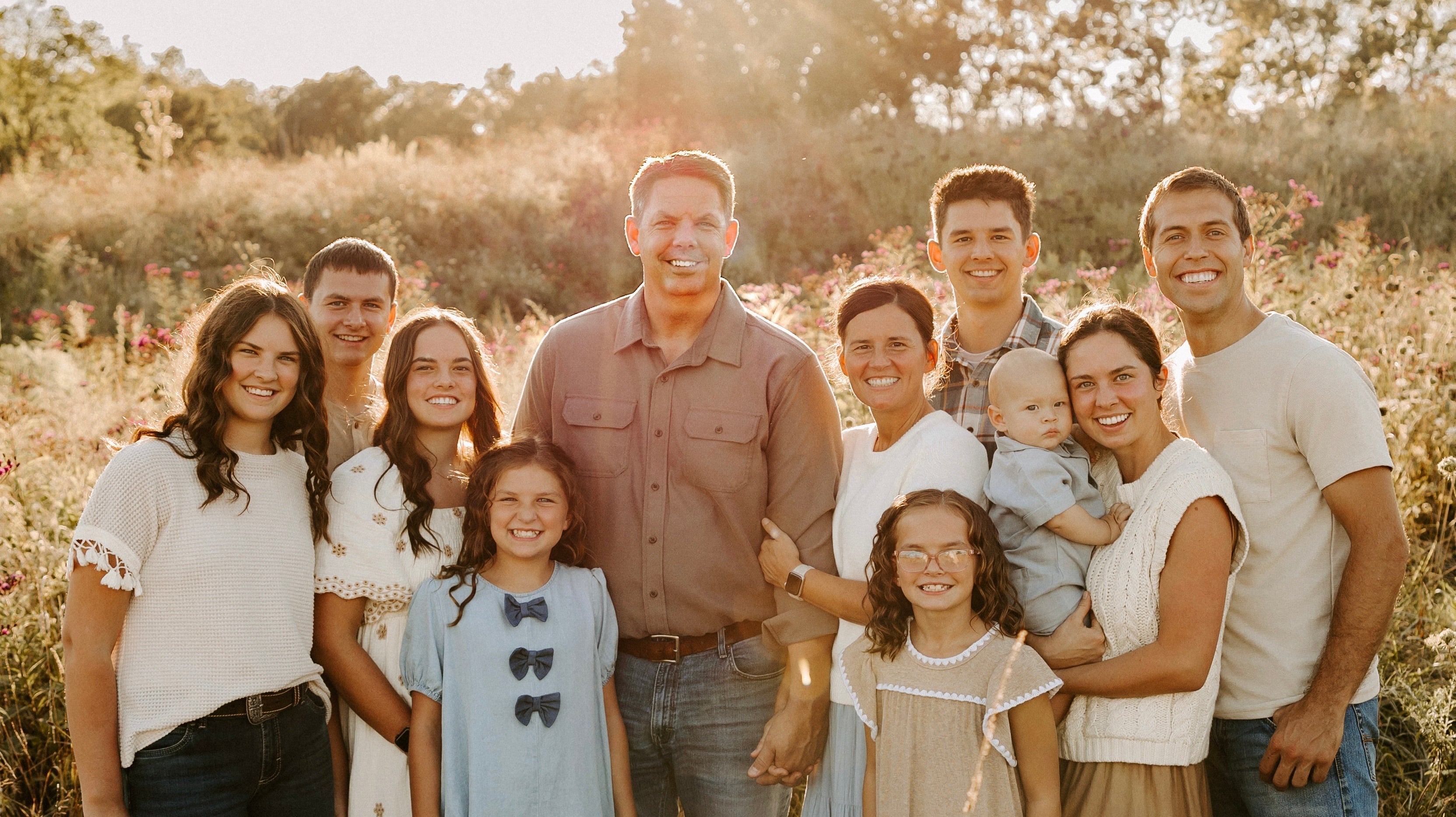 Family group wearing modest Salt and Honey dresses and skirts in a sunlit wildflower field