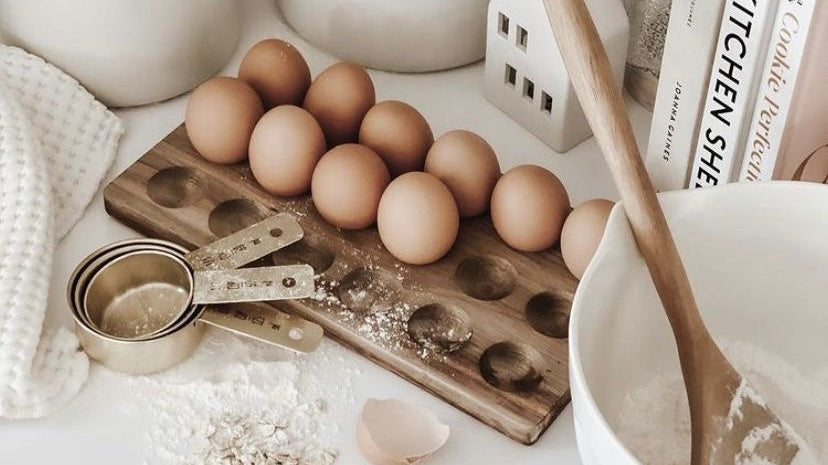 Farm fresh eggs, measuring cups, and baking ingredients on a clean kitchen counter.