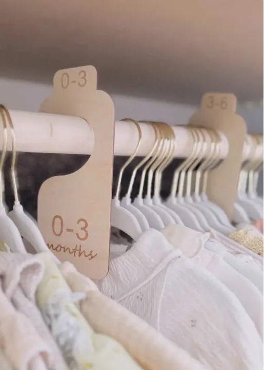 Baby clothes on hangers with size tags on a rack