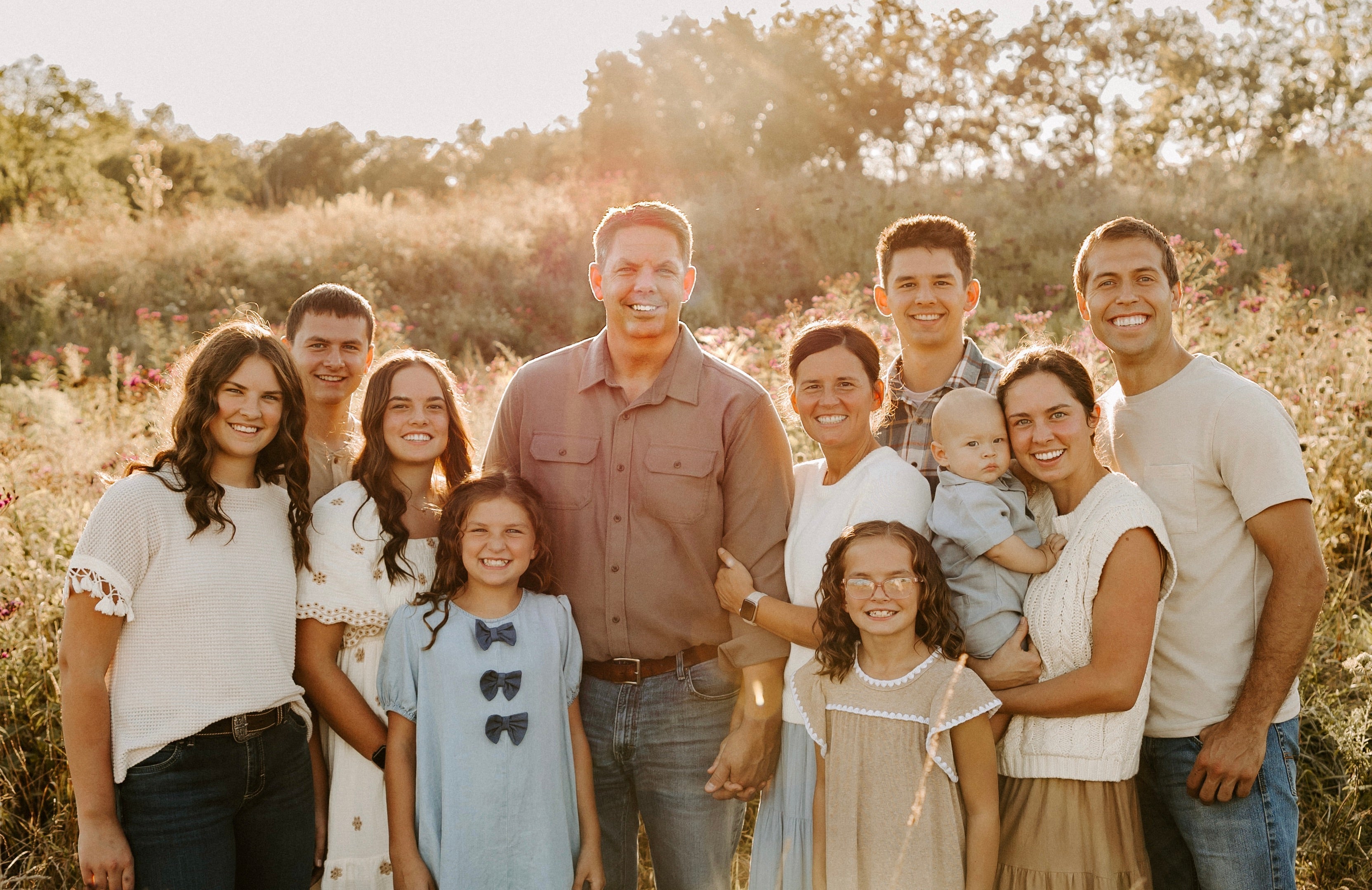 Family group wearing modest Salt and Honey dresses and skirts in a sunlit wildflower field