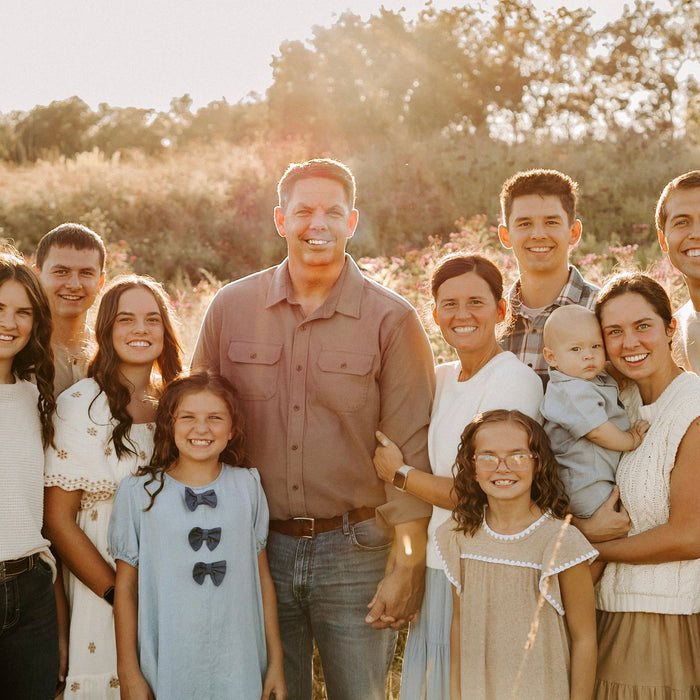 Family group wearing modest Salt and Honey dresses and skirts in a sunlit wildflower field