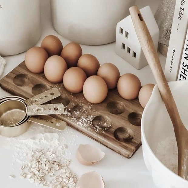 Farm fresh eggs, measuring cups, and baking ingredients on a clean kitchen counter.