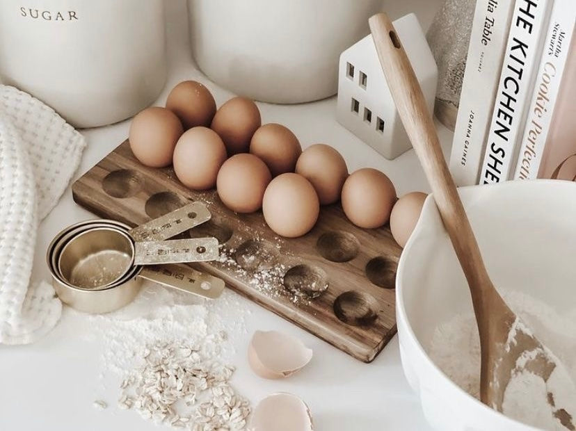 Farm fresh eggs, measuring cups, and baking ingredients on a clean kitchen counter.