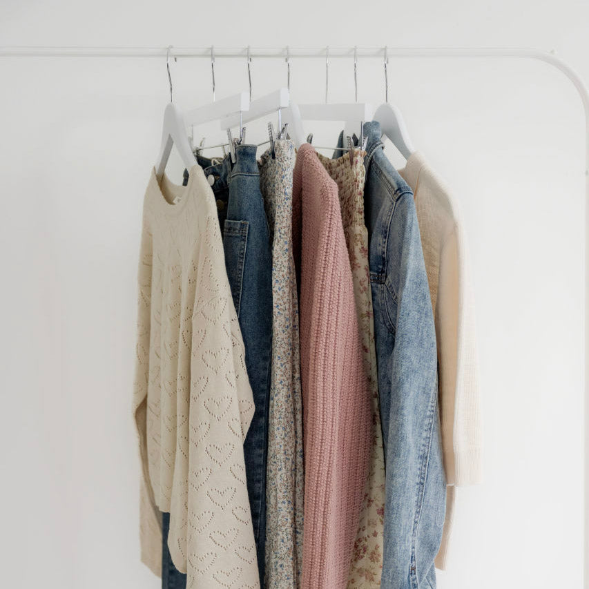 Modest women’s skirts and sweaters in neutral and denim tones hanging on a white rack