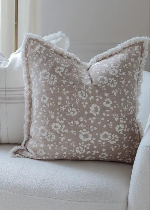 Floral patterned pillow on a white sofa with a neutral background