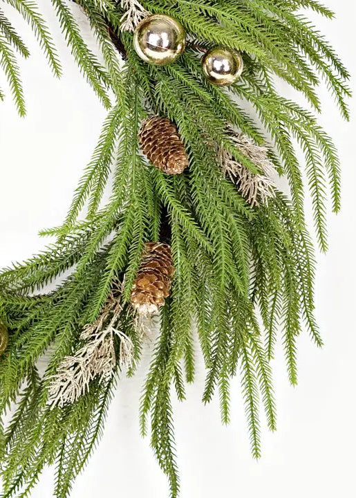 Decorative greenery with gold ornaments and pinecones on a white background