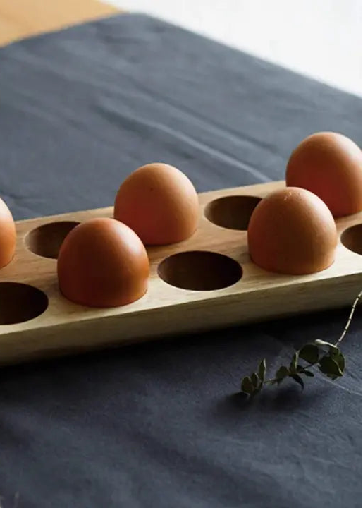 Wooden egg holder with brown eggs on a dark surface