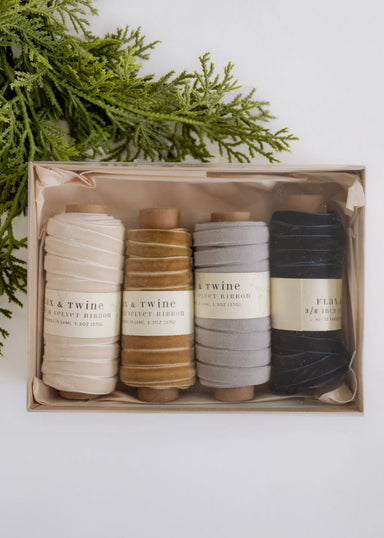 Set of yarn spools in a box with greenery on a white background