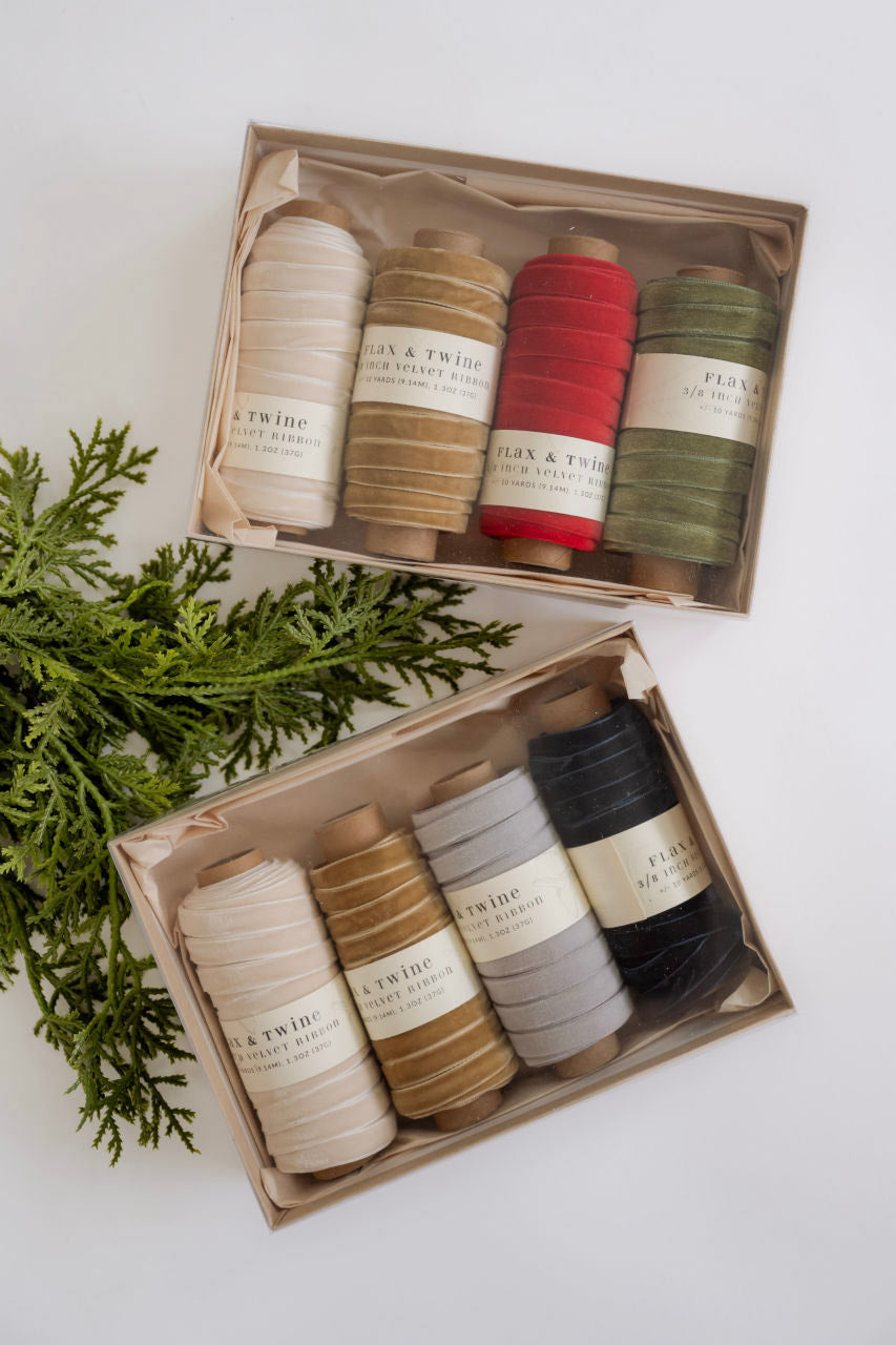 Set of yarn rolls in a box with a branch of greenery on a white background