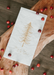 White napkin with gold tree design and text on a wooden surface with red berries