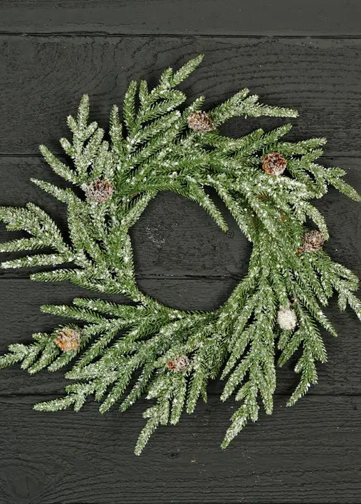 Green artificial wreath with pinecones on a dark wooden background