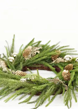 Green Christmas wreath with gold pinecones and white berries on a white background