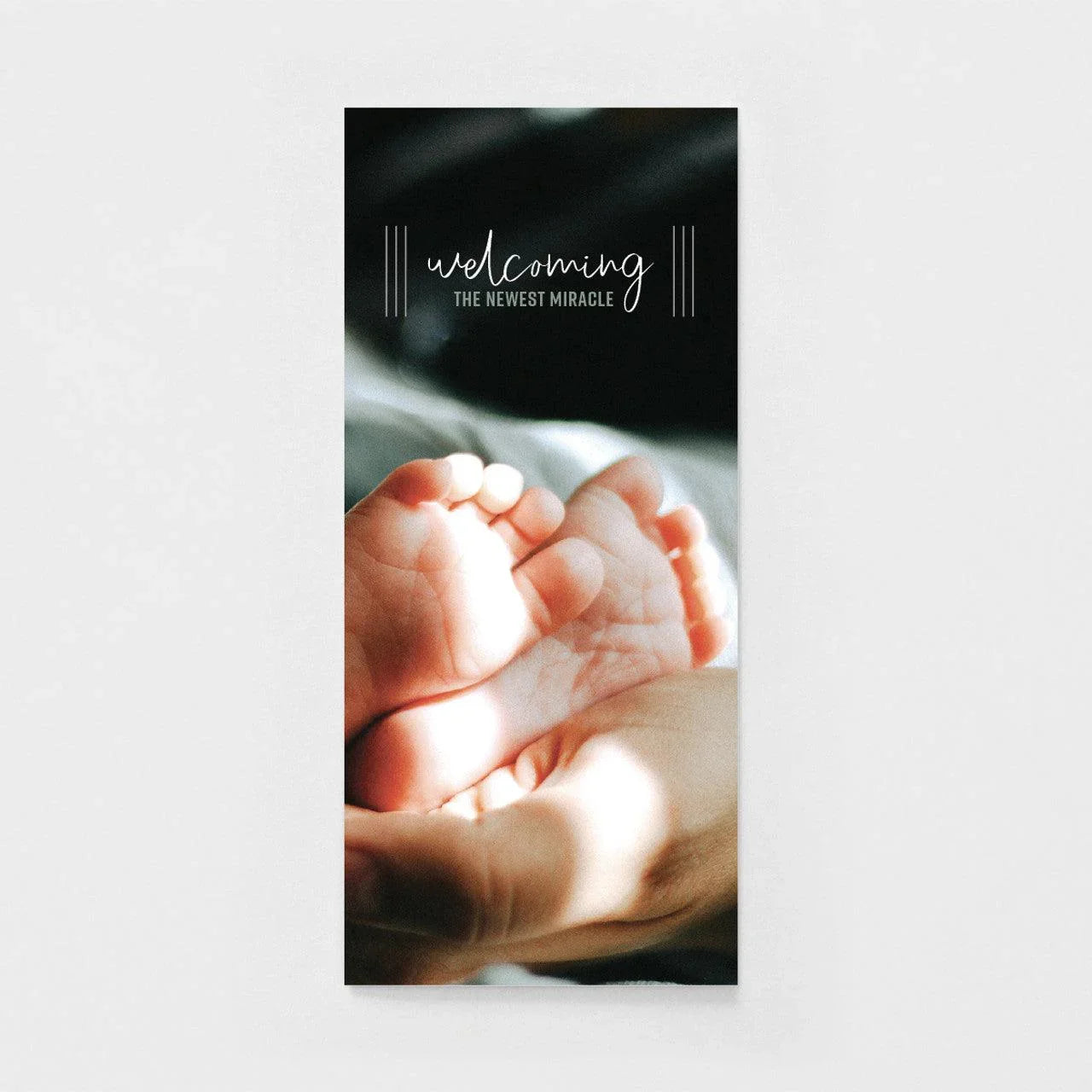 Greeting card with baby feet in hands, text 'welcoming the newest miracle', soft lighting